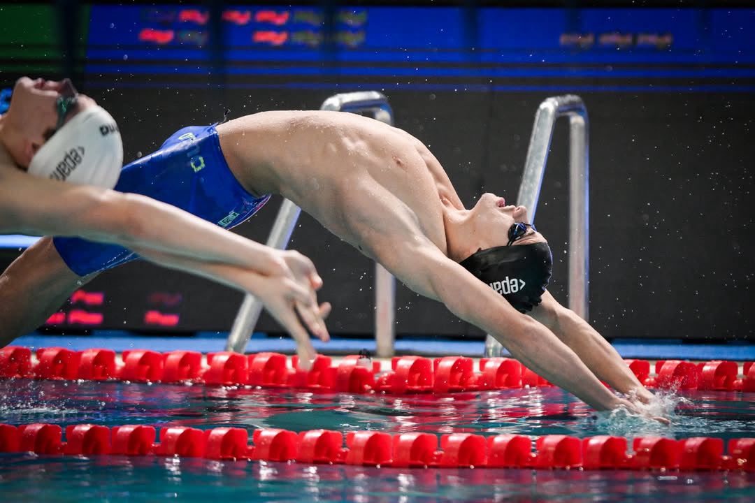 Klint Hoxha entering the water off the backstroke start